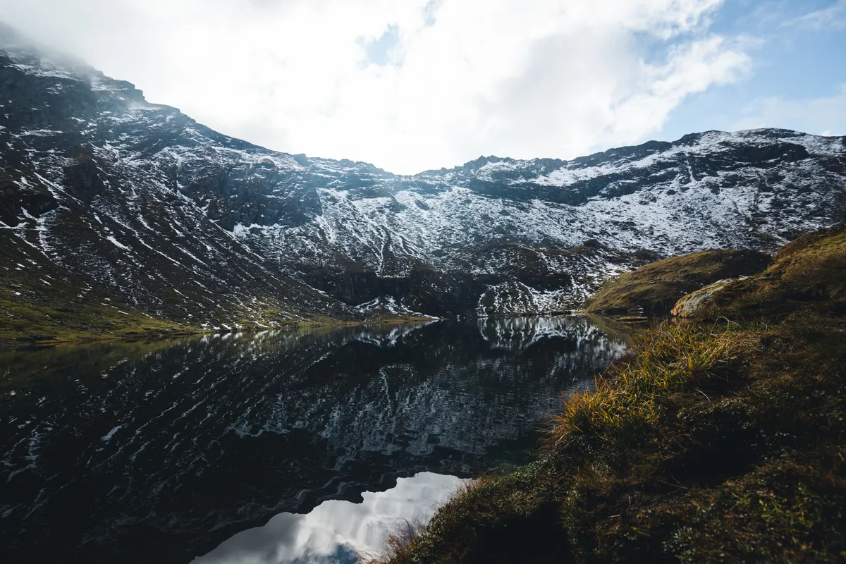 Mountain lake reflecting snowy peaks.
